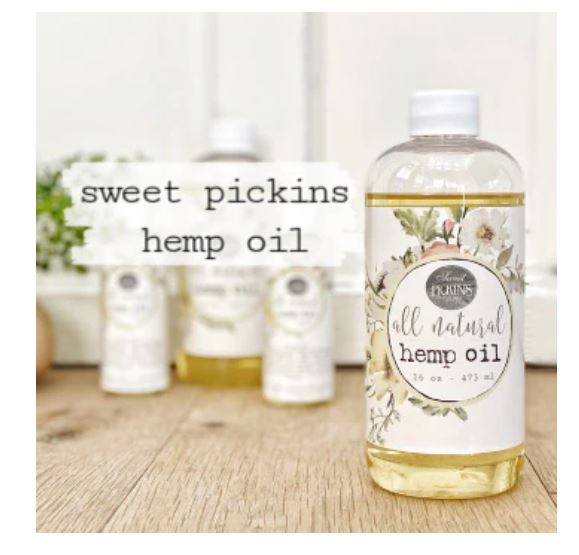 Bottle of Sweet Pickins hemp oil with a floral label on a wooden surface.
