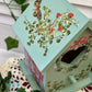Decorative birdhouse with floral design and butterfly on a textured surface