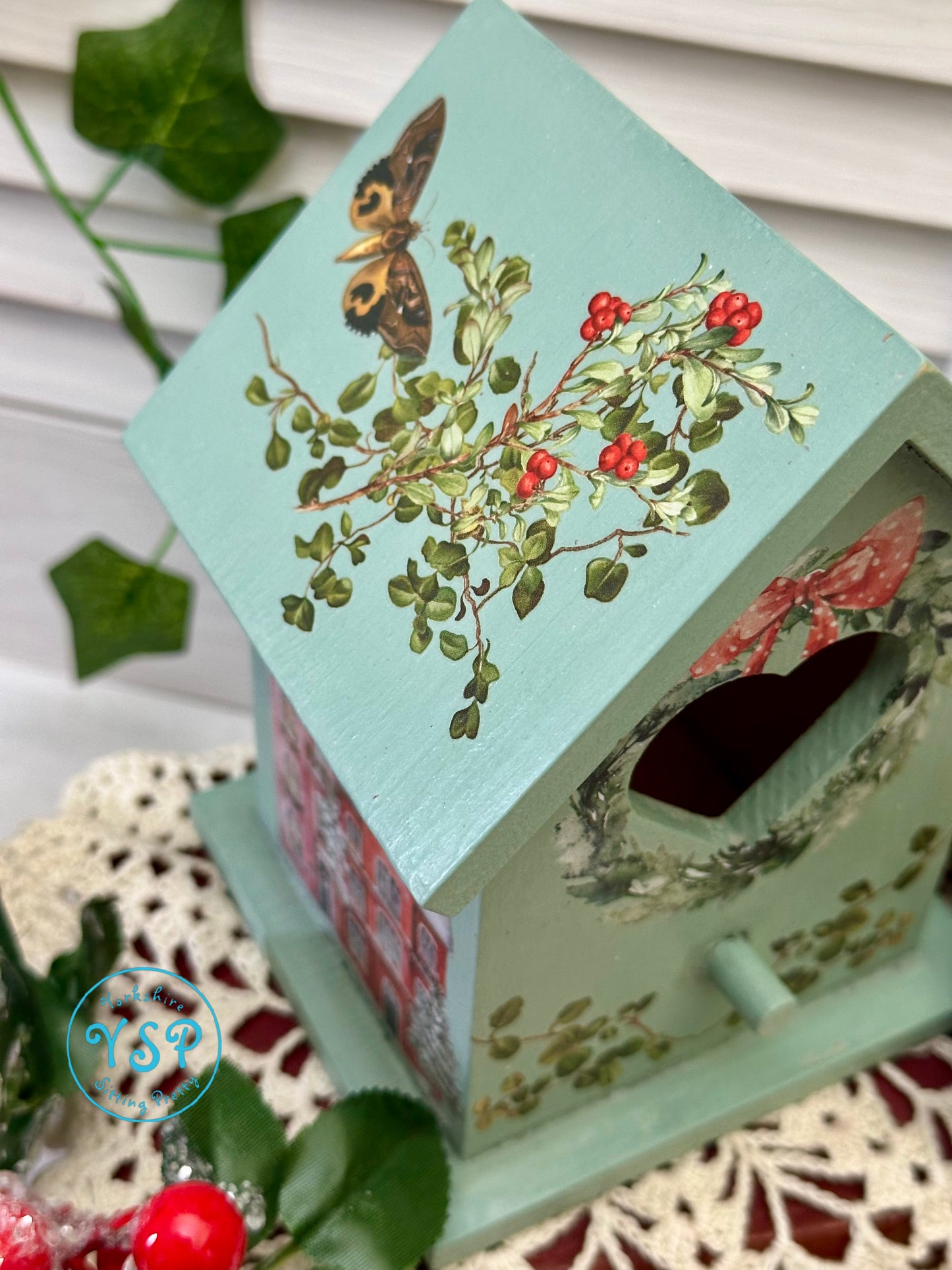 Decorative birdhouse with floral design and butterfly on a textured surface