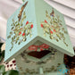 Decorative birdhouse with floral designs on a white background