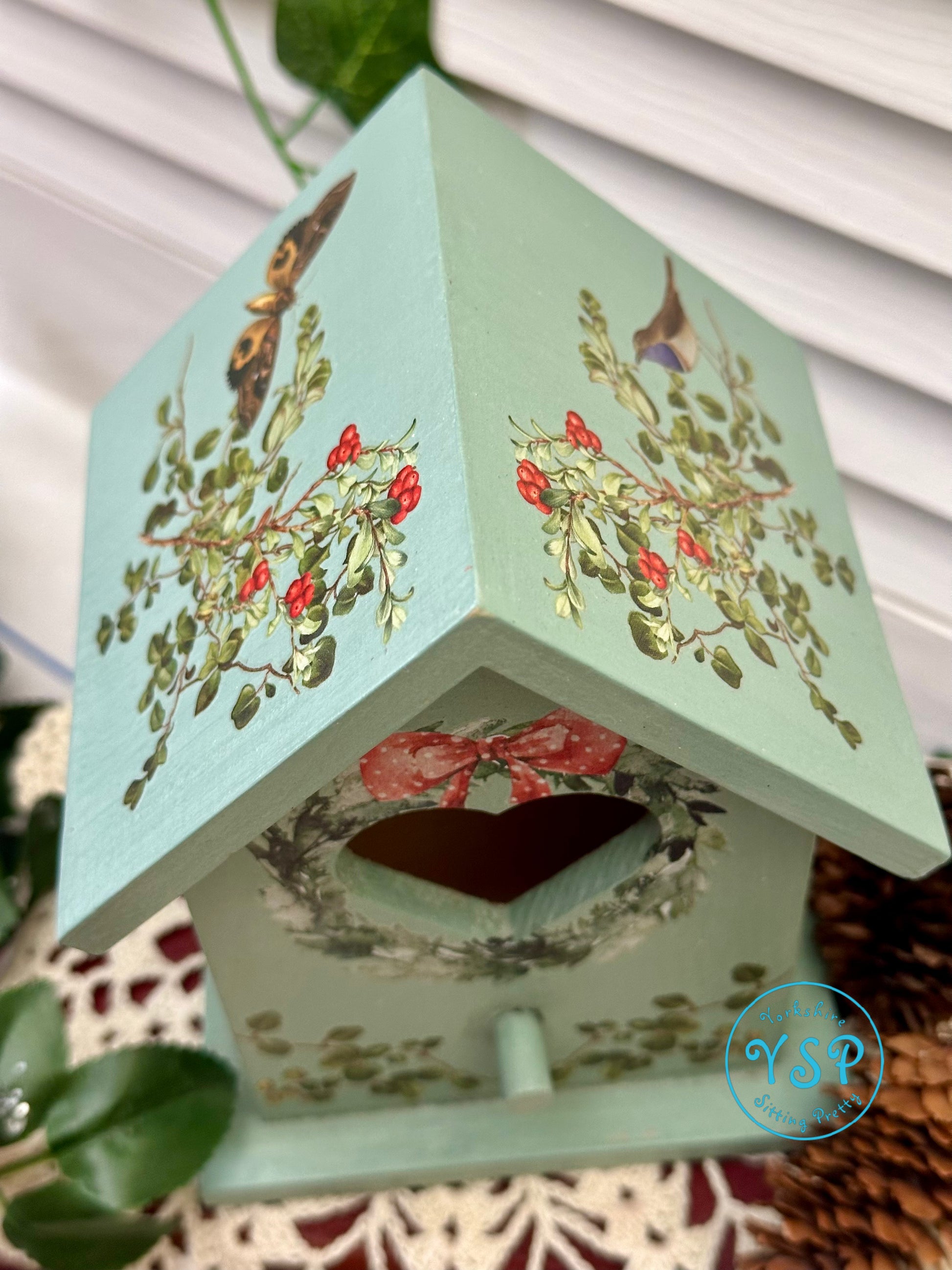 Decorative birdhouse with floral designs on a white background