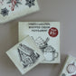 Three vintage-style Christmas-themed matchboxes arranged on a neutral beige background. The center matchbox reads 'Marshmallows, Whipped Cream, Peppermint' and shows a mug illustration with a red 'Only 25c' stamp. From Iron Orchid Designs