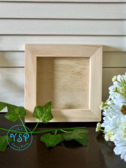 Wooden picture frame on a wooden surface with greenery and flowers by Iron Orchid Designs