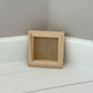 Small wooden frame on a white surface with a grey wall background by Iron Orchid Designs