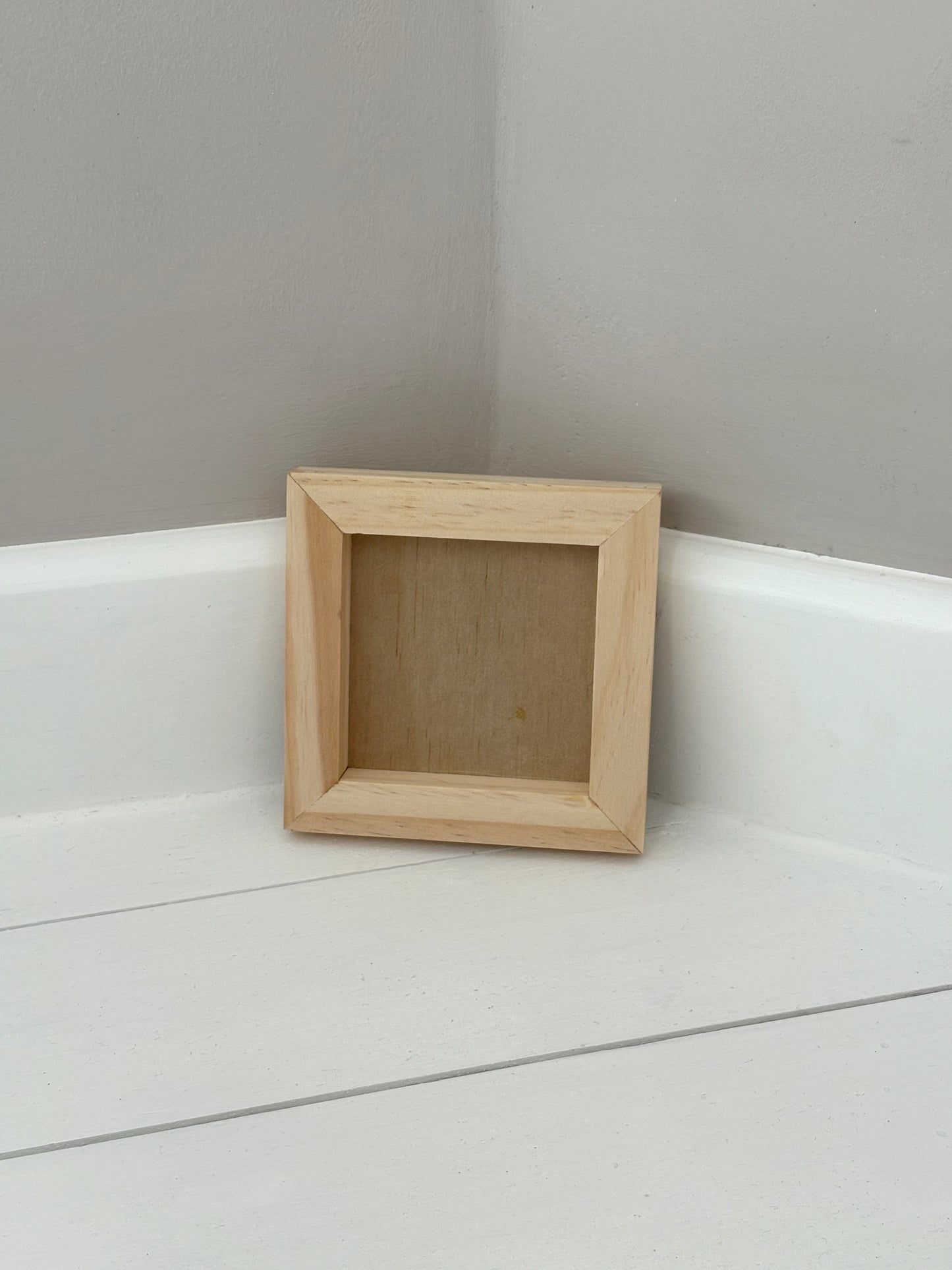 Small wooden frame on a white surface with a grey wall background by Iron Orchid Designs