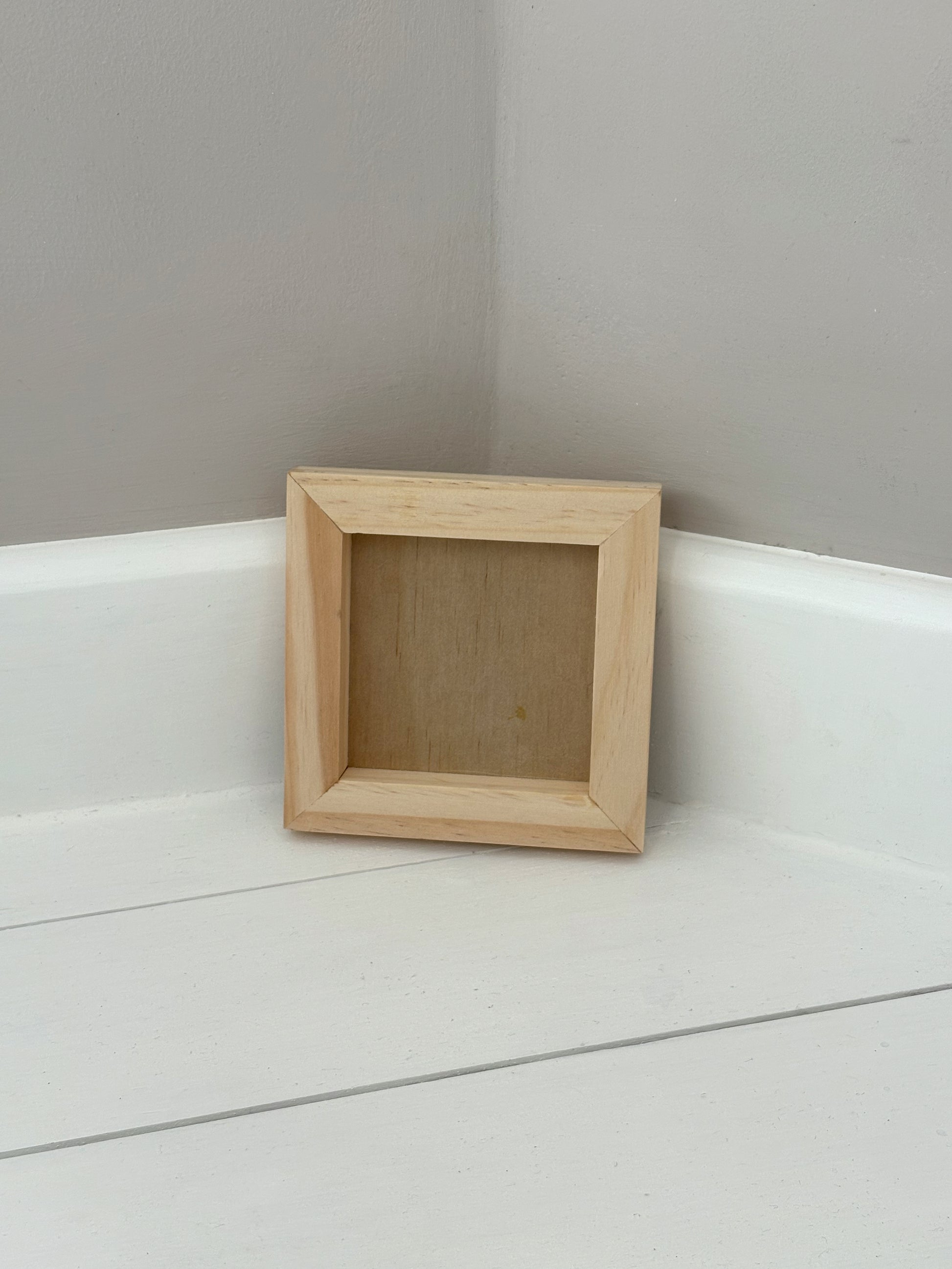 Small wooden frame on a white surface with a grey wall background by Iron Orchid Designs