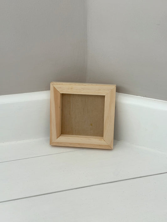 Small wooden frame on a white surface with a grey wall background by Iron Orchid Designs