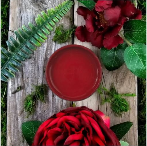 Pot of red paint on a wooden table surrounded by different leaves. Paint Couture