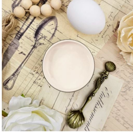 Pot of cream coloured paint on a table next to a decorative spoon. Paint Couture