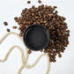 Dark brown paint in a pot surrounded by coffee beans. Paint Couture