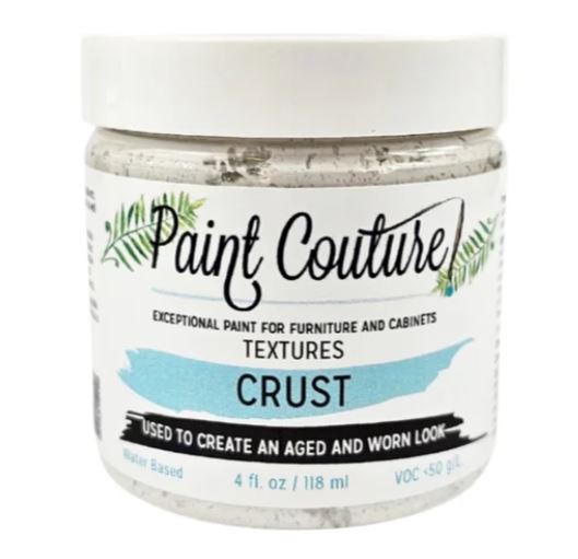 A jar of Paint Couture Textures Crust paint, featuring a white lid and a white label with black and light blue text, set against a plain white background.
