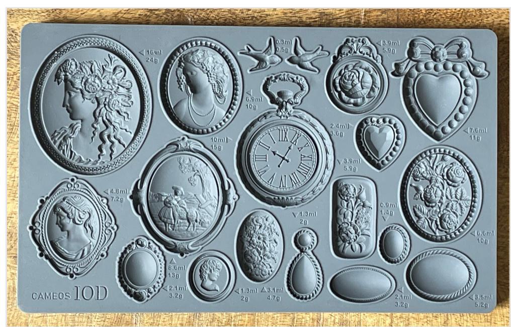 Iron Orchid Designs Cameos Mould. Grey mould laying on a wooden surface. Beautiful intricate designs of cameos, hearts and flowers.