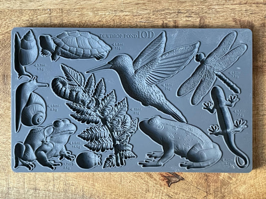 Iron Orchid Designs Dewdrop Pond grey Mould laying on a wooden surface. Highly detailed hummingbird, dragonfly, fern, frog, tortoise designs.