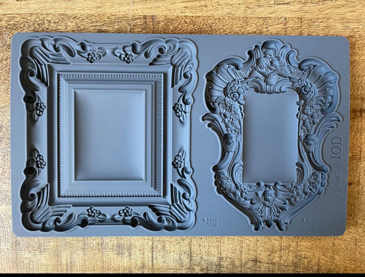 Iron Orchid Designs Frames 2 grey silicone mould laying on a wooden surface. The mould has two intricate frame designs
