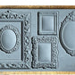 Iron Orchid Designs Frames grey Mould laying on a wooden surface. The intricate designs of the frames are displayed 
