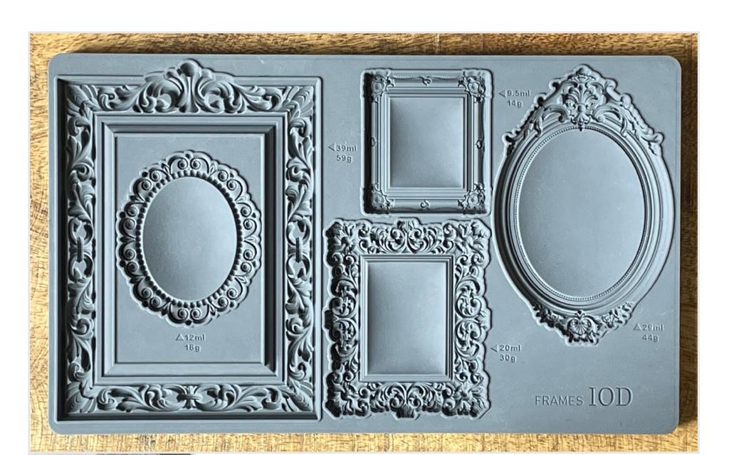 Iron Orchid Designs Frames grey Mould laying on a wooden surface. The intricate designs of the frames are displayed 