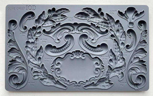 Iron Orchid Designs Olive Crest grey silicone mould on a white background. There are intricate designs of olive branches, swags, curls and a decorative label