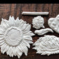 White clay castings from Iron Orchid Designs Sunflowers Mould laying on a wooden surface
