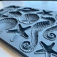 A close up photograph of Iron Orchid Designs Seashells grey Mould showing the details and varieties of the shells