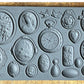 Iron Orchid Designs Cameos Mould. Grey mould laying on a wooden surface.