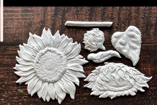 White clay castings from Iron Orchid Designs Sunflowers Mould laying on a wooden surface