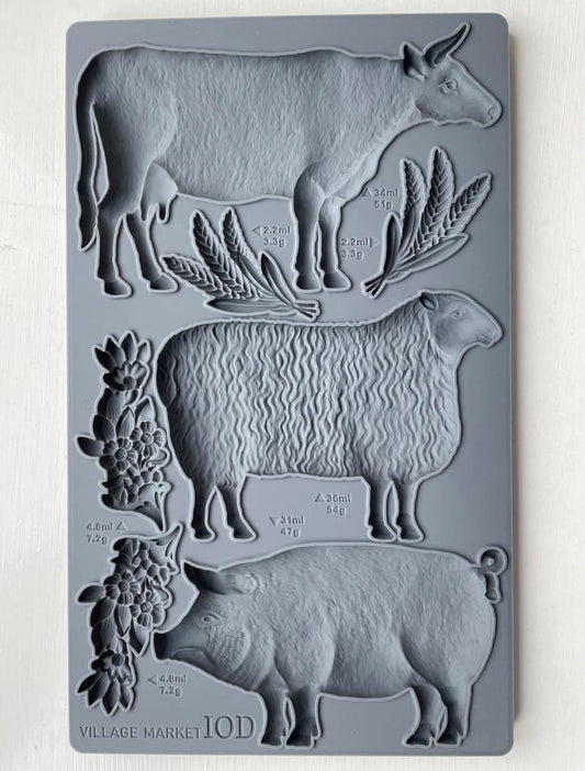 Iron Orchid Designs Village Market grey Mould with cow, sheep and pig laying on a wooden surface
